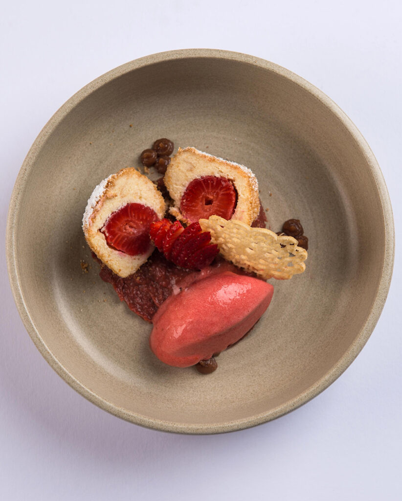 berry sorbet with strawberries and sponge dessert plated with sauce and crisp garnish
