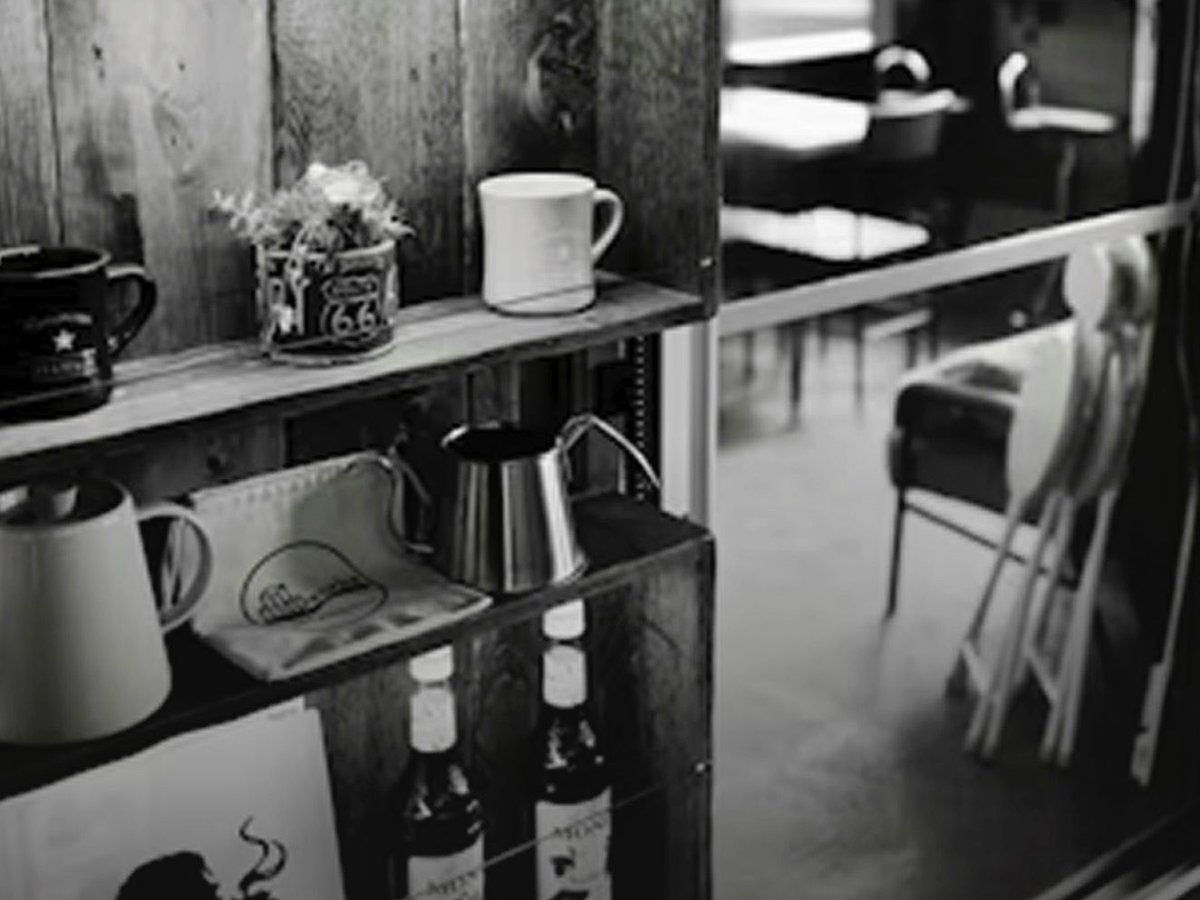 A characterful café shelf with mugs, a pour-over kettle and syrup bottles