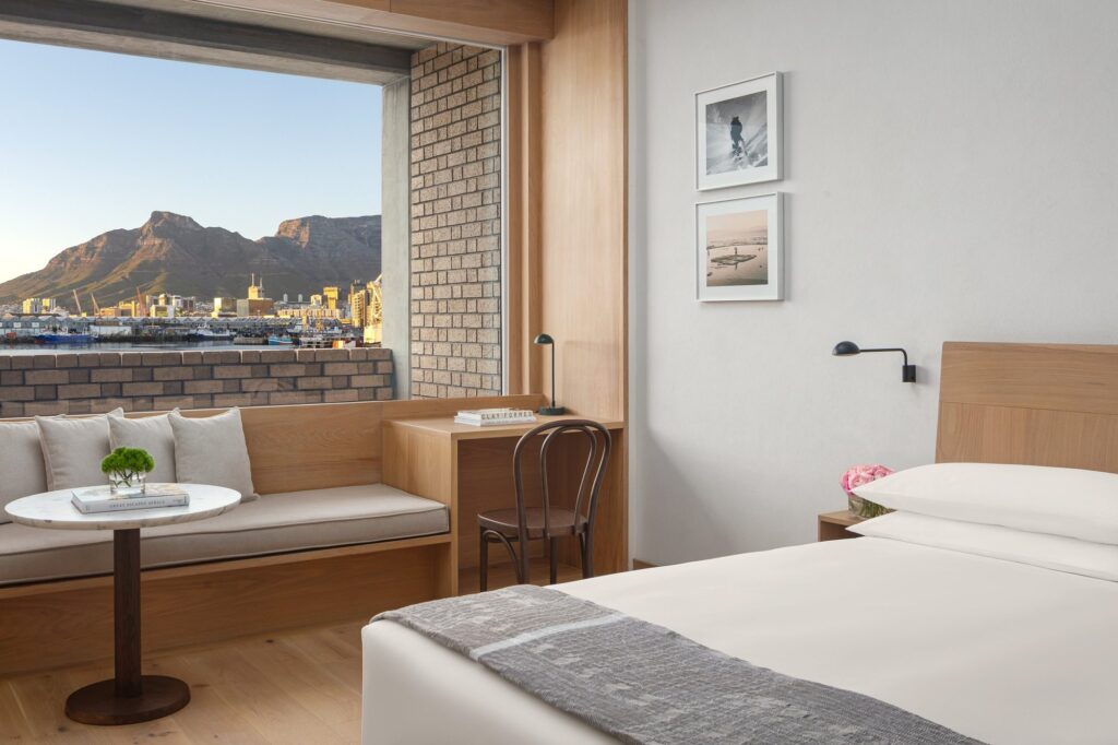 A guestroom with a window seat looking across the harbour to Table Mountain