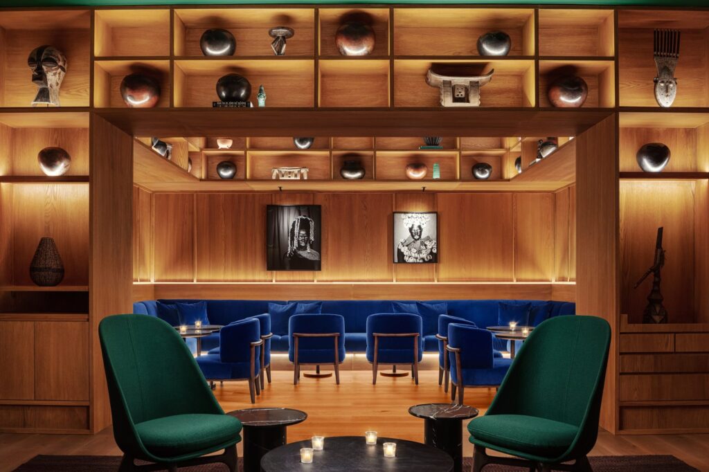 Punch Room: blue velvet banquettes, green armchairs and black-and-white portraits in warm wood panelling