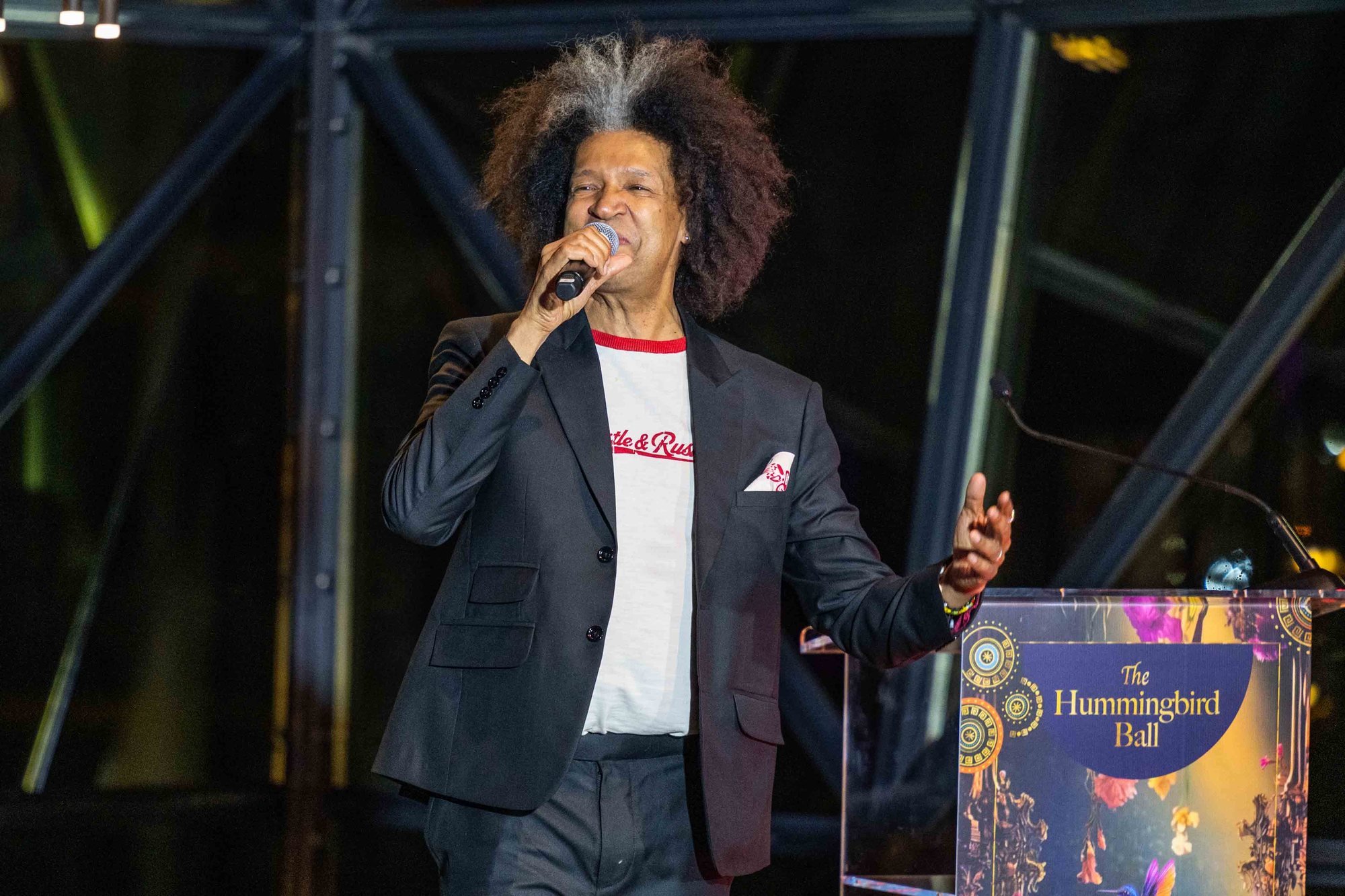 Comedian Marc Lottering performing with a microphone beside the Hummingbird Ball lectern.