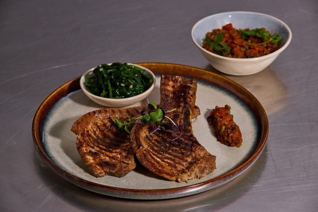 A grilled main course plated with greens and a relish