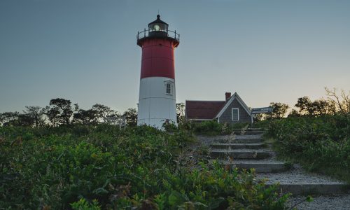 red and white lighthouse near white house under blue sky during daytime